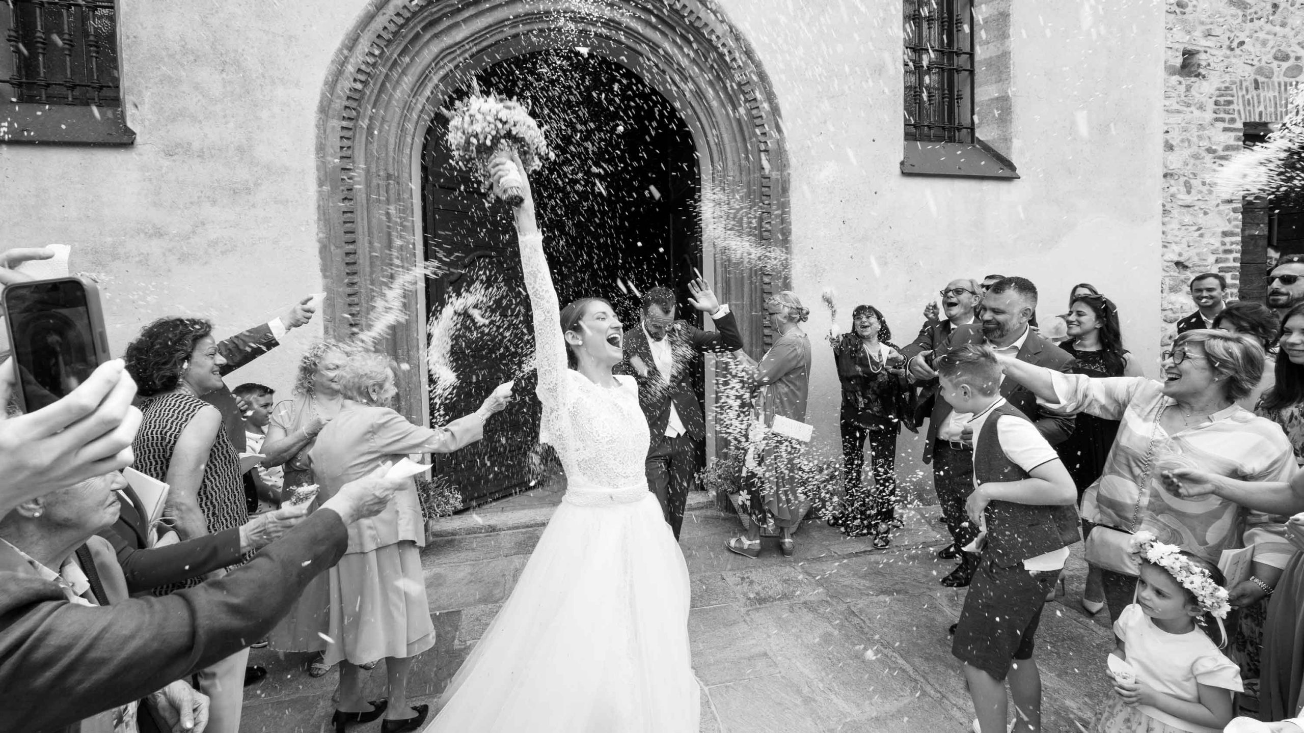 fotografo matrimonio reportage Varese Milano con sposi all'uscita dalla chiesa sommersi dal riso